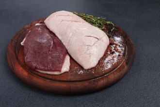 Fresh raw duck breasts, on a wooden chopping board, with herbs and spices, no people