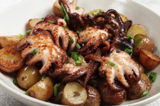 Baby grilled octopus with golden baked potatoes and fresh herbs, Maltese cuisine, homemade, no