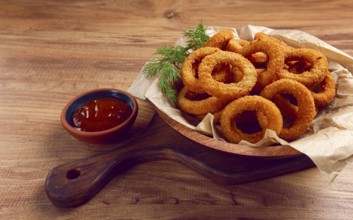 Deep fried onion rings, appetizer, with tomato sauce, on a wooden table, no people, favorite dish