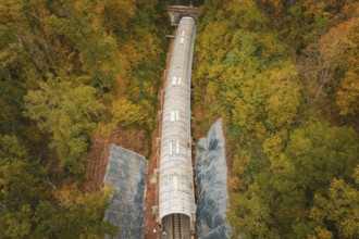 Railway line with safety tunnel nestled in an autumnal forest, Herman-Hesse-Bahn construction site,