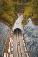 Railway line with partial tunnel in autumn surroundings with construction workers,