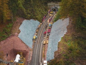 Working at the tunnel entrance to a railway line, with construction equipment and soil in an autumn