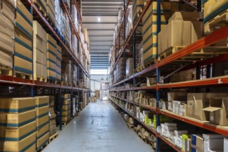 Storage warehouse interior filled with numerous cardboard boxes and products stacked on tall racks,