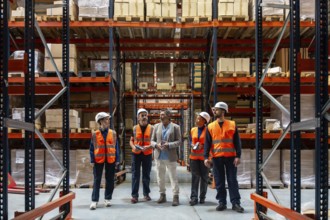 Diverse team of logistics workers and a manager discussing operations and inventory control inside