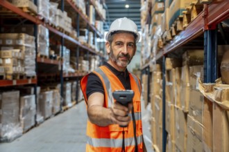 Warehouse worker wearing safety helmet and vest, holding scanner, checking inventory and managing
