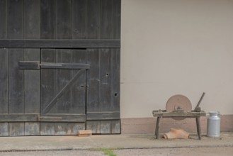 A whetstone and a bucket in front of an old rustic barn door, Hohwiller, Alsace, France