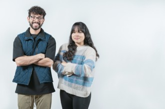 Smiling young couple with crossed arms looking at camera, isolated. Cheerful young multiethnic