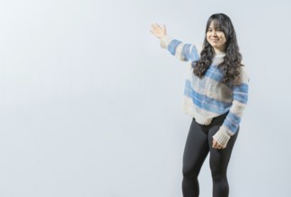 Happy girl welcoming you on isolated bakground. Smiling young woman presenting something, isolated