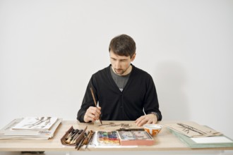 An artist is focused on creating artwork at a neatly organized table