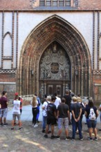 Tourist group in front of the portal of St. Nicholas Church, also St. Nicholas Church, in the city