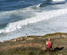 Tourists watch the waves of the Atlantic on the rocky plateau of Sito, also known as Forte São