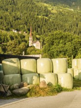Agricultural structures with hay bales sealed in plastic near a farm on the outskirts of Oetz in