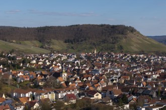 View of city with red roofs, surrounding green hills and clear blue sky, Korb im Rems Valley,