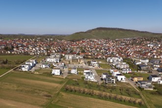View of city with new development area, red roofs and surrounding green hills in the background,