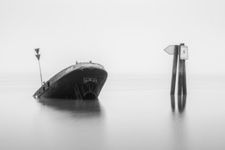 Long exposure of the partially sunken MS Uwe shipwreck in the Elbe on Falkensteiner Ufer in fog and
