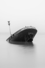 Long exposure of the partially sunken MS Uwe shipwreck in the Elbe on Falkensteiner Ufer in fog and