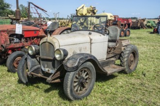 Older automobile converted into agricultural tractor at exhibition on old-fashioned harvest