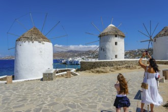 Mykonos, Cyclades, Greece - Tourists photograph the six sixteenth-century windmills lined up on a