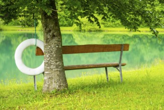 Park bench standing beside beside and with view onto Lake Elisabethsee on a cloudy day in spring,