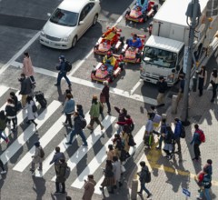 People cross zebra crossings, people in costumes ride small go-kart racing cars, Shibuya Crossing,