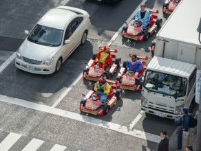 People in costumes ride small go-kart racing cars, Shibuya Crossing, Shibuya, Tokyo