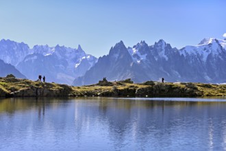 A group of hikers at Lac de Chésserys, behind the snow-covered Mont Blanc massif,