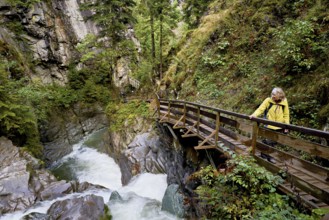 Female hiker standing on wooden walkway, Diosaz mountain river in the gorge, Gorges de la Diosaz,