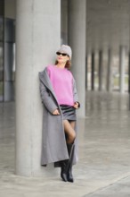 Urban street style with bold colors and modern fashion by a concrete pillar in an urban setting