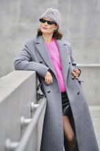A fashionable model stands confidently on a rooftop, showcasing urban street style