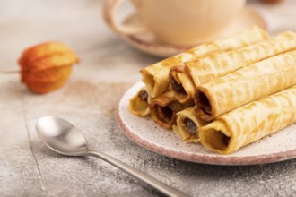 Waffles with caramel on brown concrete background and orange linen textile, cup of coffee, side