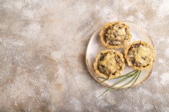 Tartlets with meat and cheese on brown concrete background. top view, flat lay, copy space
