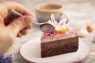 Chocolate cake with hand on brown concrete background, cup of coffee, side view, close up,