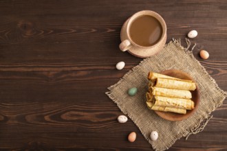 Waffles with caramel on brown wooden background and linen textile, cup of coffee, top view, flat