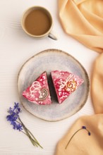 Chocolate cake on white wooden background and orange linen textile, cup of coffee, top view, flat
