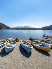 Rowing boats on shore, view across the lake to Mt Fuji volcano, Motosu Lake, Yamanashi Prefecture,