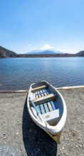 Rowing boat on shore, view across the lake to Mt Fuji volcano, Motosu Lake, Yamanashi Prefecture,