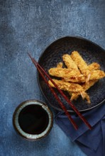 Shrimp in tempura, deep fried, on a black plate, with soy sauce, close-up, top view, no people