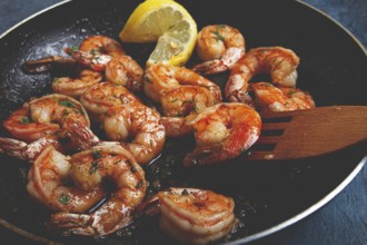 Fried tiger prawns, jumbo, in garlic sauce, in butter, with herbs, in a frying pan, homemade, no