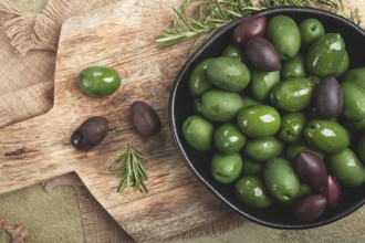 Chalkidiki olives, classic Greek green olives, in a bowl on a cutting board, top view, without