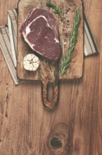 Raw steak, beef steak, rib eye steak, on a cutting board, freshly frozen, with spices and herbs, on