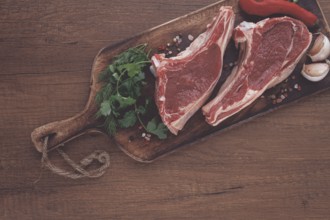 Freshly sliced lamb chops, with herbs and vegetables, on a wooden board, ready to cook, on a wooden