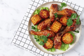 Fried chicken drumsticks, Mexican style, with corn, on a plate, close-up