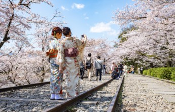 Keage Incline, two Japanese women wearing kimonos taking selfies on old tracks, cherry trees
