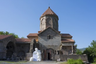 Historic church with tiled roof and blue sky in the background surrounded by greenery, Wahanavank