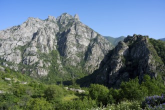 High rocks and mountains with green vegetation under clear summer sky, landscape with Baghaberd