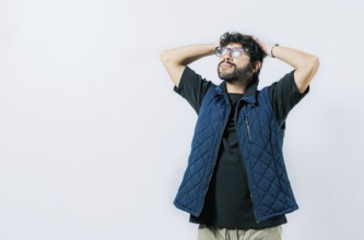 Relaxed young man in glasses with hands behind neck, isolated. Smiling calm guy with hands behind