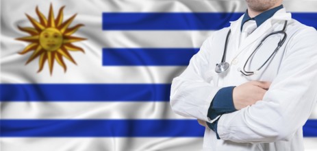 Uruguay healthcare concept. Male doctor on Uruguay flag. Doctor with crossed arms on Uruguay flag