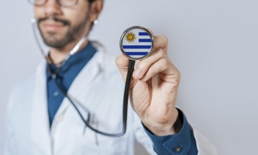Doctor holding stethoscope with Uruguay flag. Uruguay health and care concept. Uruguay flag on
