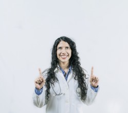 Cheerful female doctor pointing up isolated. Young female doctor looking and pointing at promotion