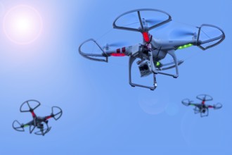Three miniature quadcopter drones, teleoperated unmanned aerial vehicles, UAV equipped with cameras